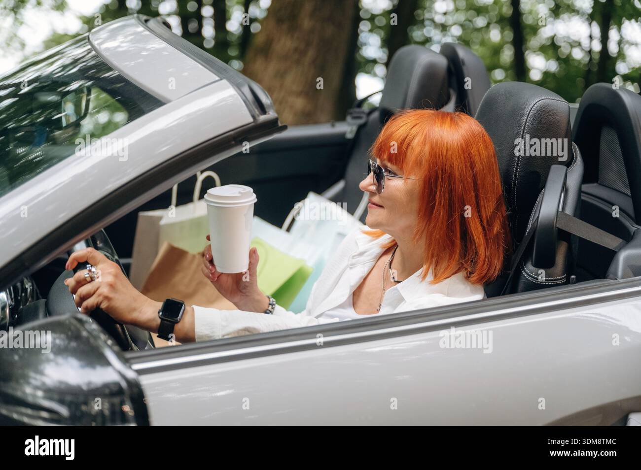 Having great time, in sunglasses. Side view of woman that is driving convertible cabriolet car. Stock Photo