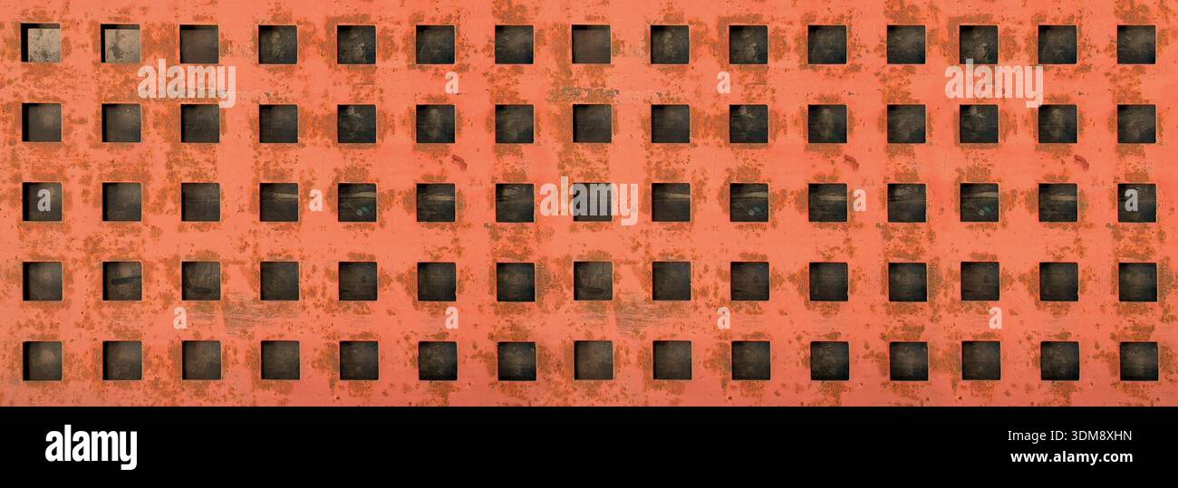 Rusty orange metal surface showing repeating square holes, creating a textured background Stock Photo