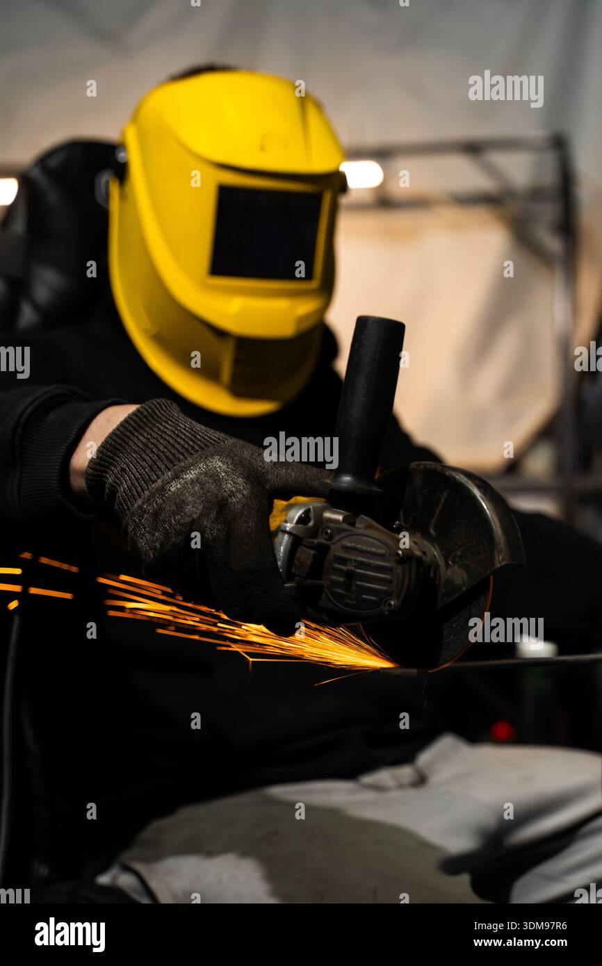 Worker grinds steel with angle grinder in factory wearing protective helmet Stock Photo - Alamy Worker grinds steel with angle grinder in factory wearing protective helmet Stock Photo - Alamy
