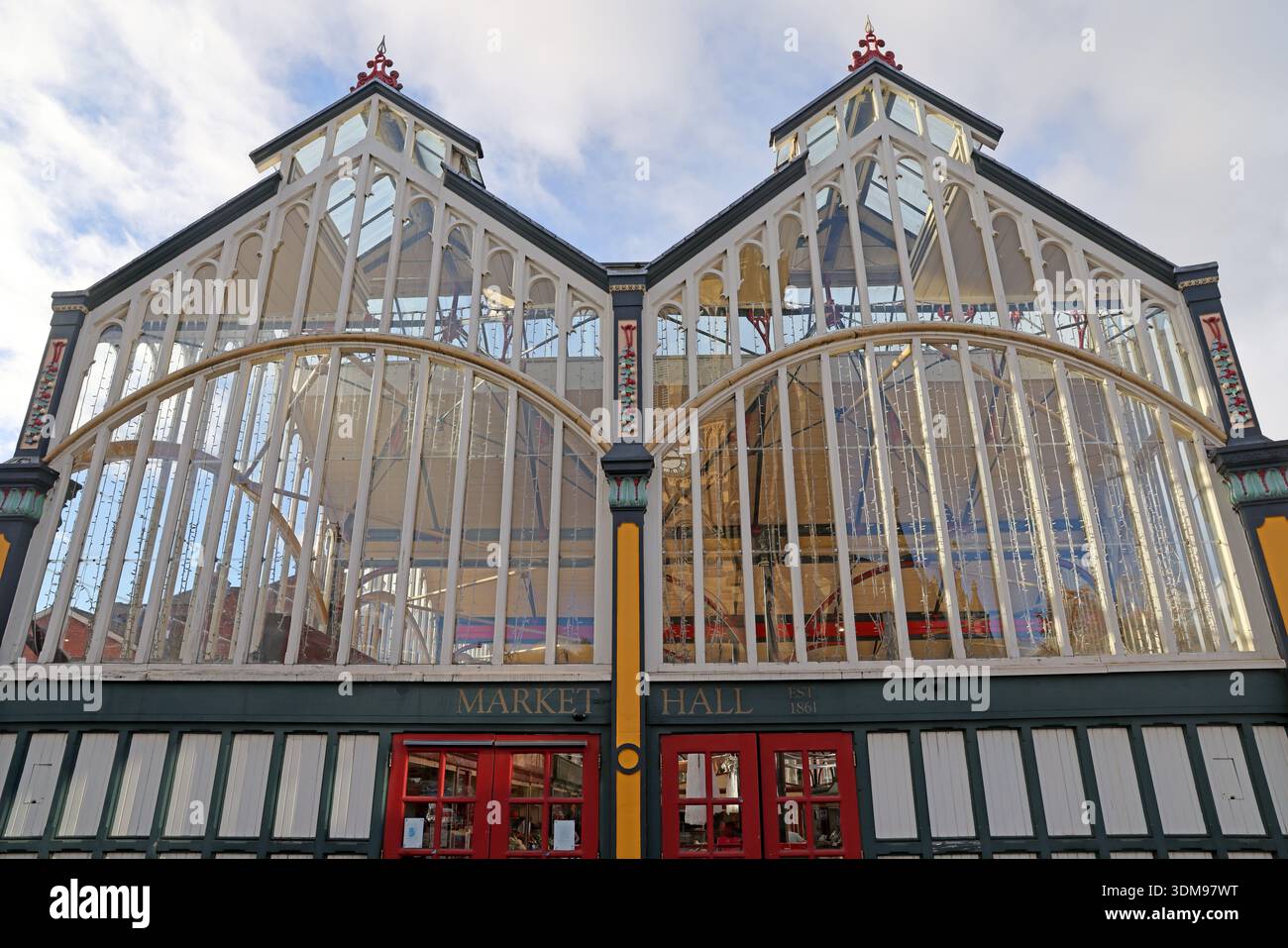 Upward view of the glass and timber sides of Stockport Market Hall in Market Place, showing the Victorian arched façade and red entrance doors Stock Photo