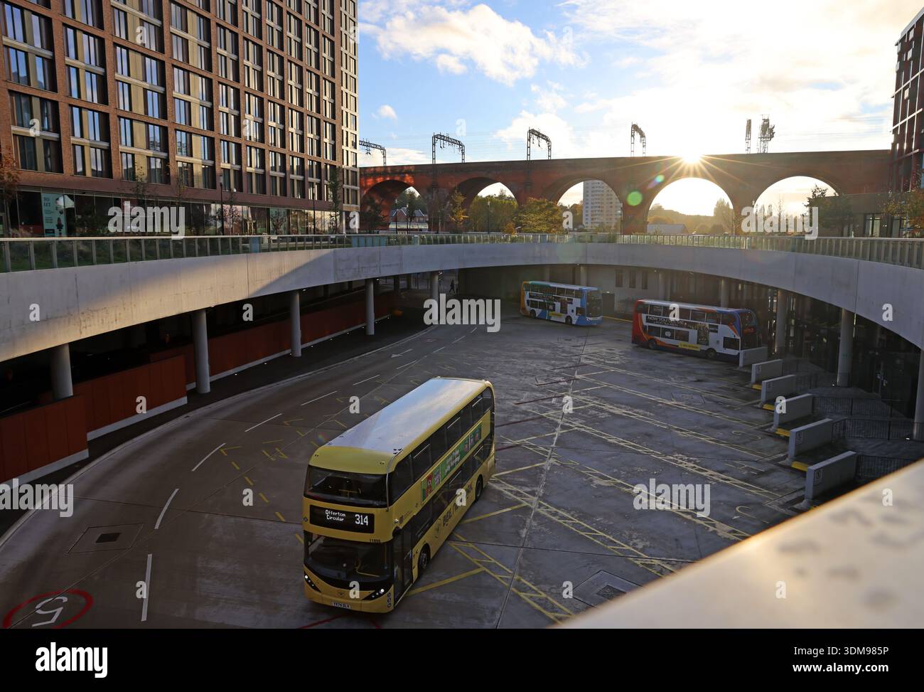 Sunset winter view over Stockport Interchange bus station with departing double decker bus and arches of Stockport railway viaduct in the background Stock Photo