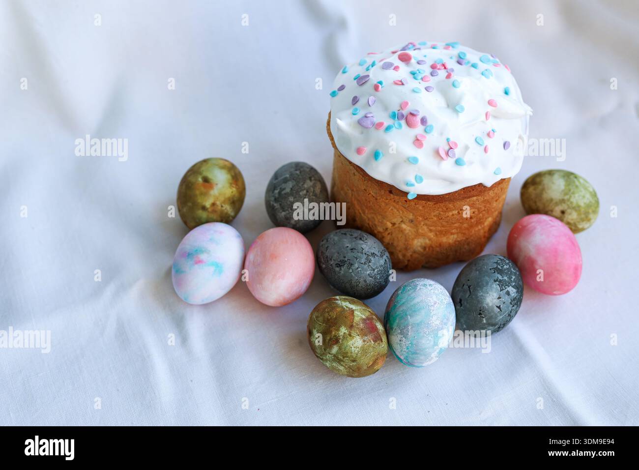 Festive Easter kulich on a light tablecloth with painted eggs, classic Easter symbol. Stock Photo