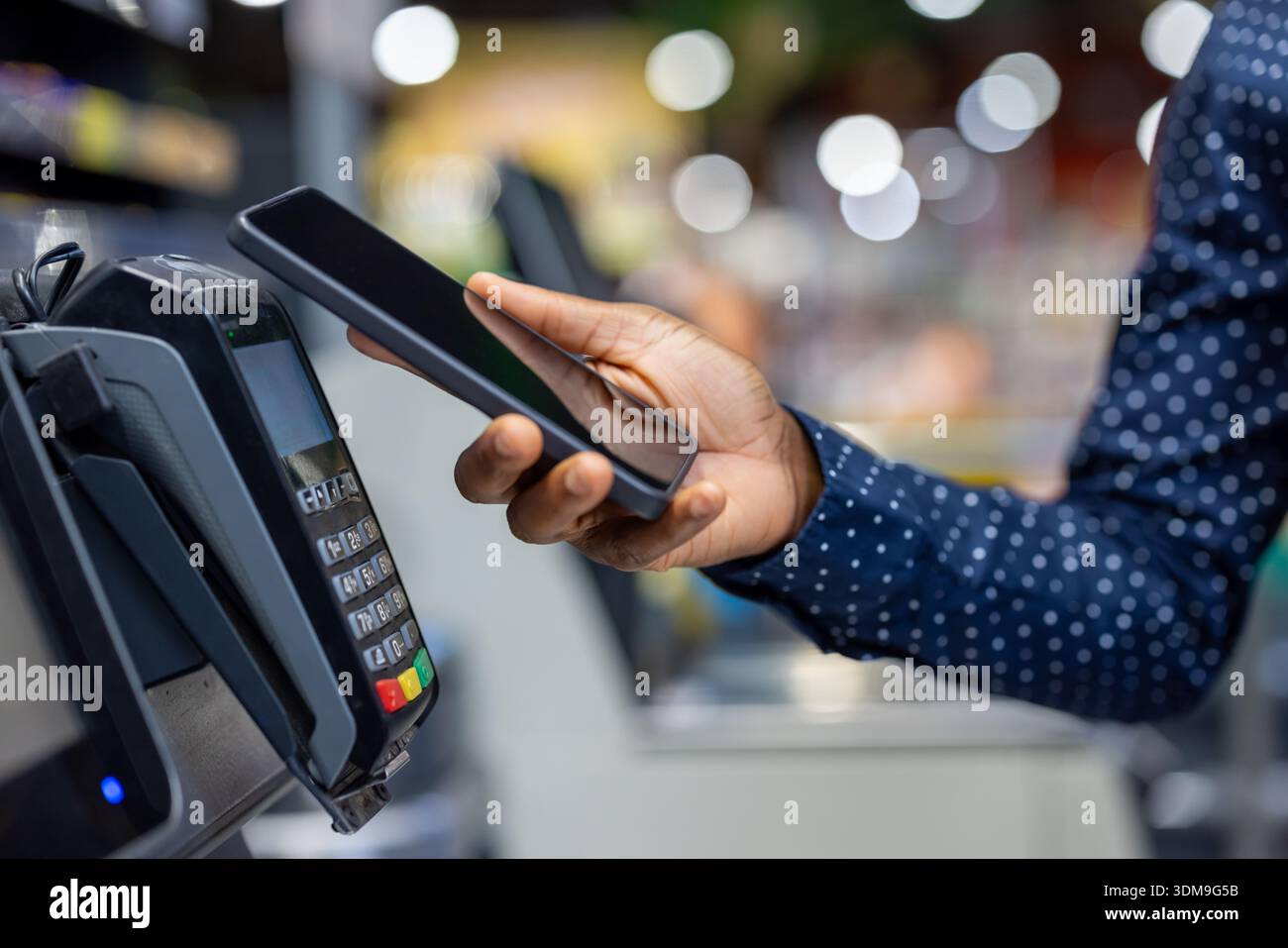 Person using a mobile phone to make a contactless payment at a point of ...