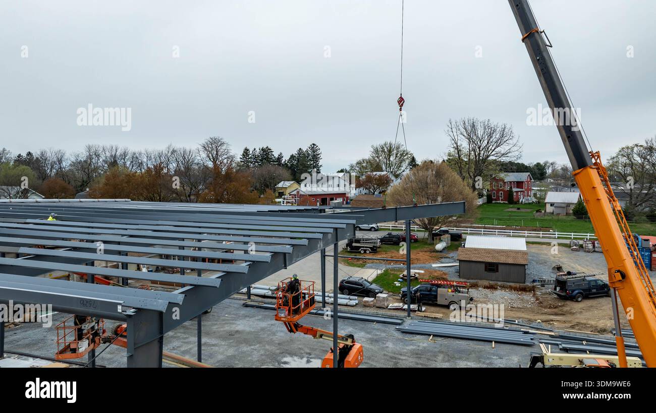 Construction workers use machinery to install steel beams in a town. A ...