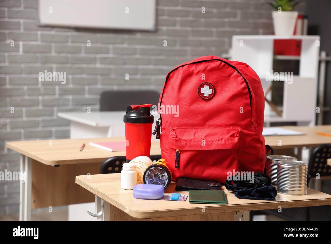 Emergency backpack with necessities on desk in classroom Stock Photo