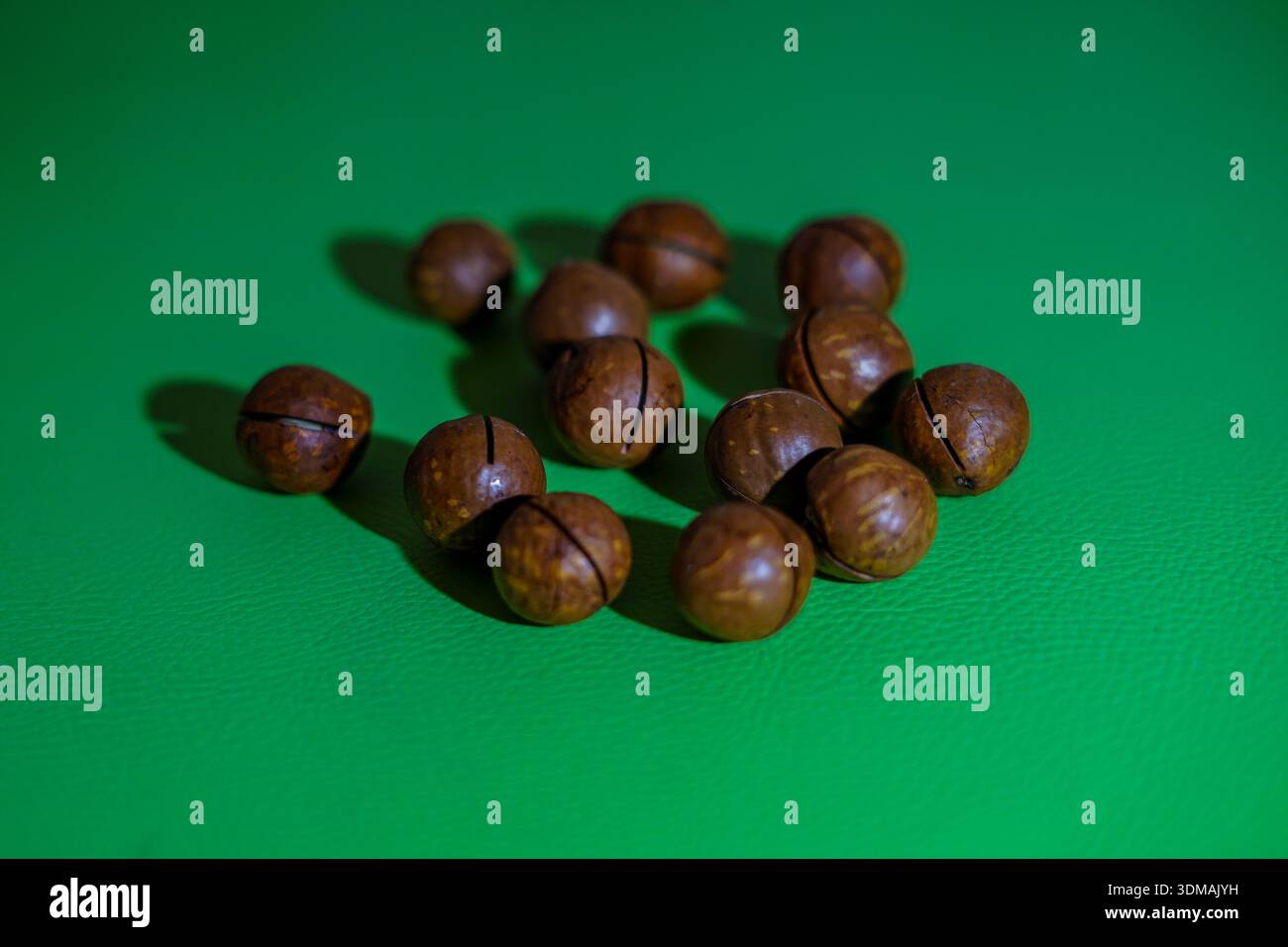 Macadamia Nuts Scattered on a Green Surface Stock Photo