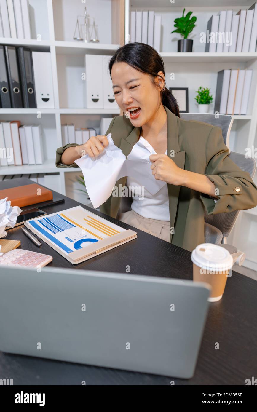 Stressed businesswoman dealing with heavy work pressure, reacting emotionally while reviewing reports and facing tight deadlines, highlighting workpla Stock Photo