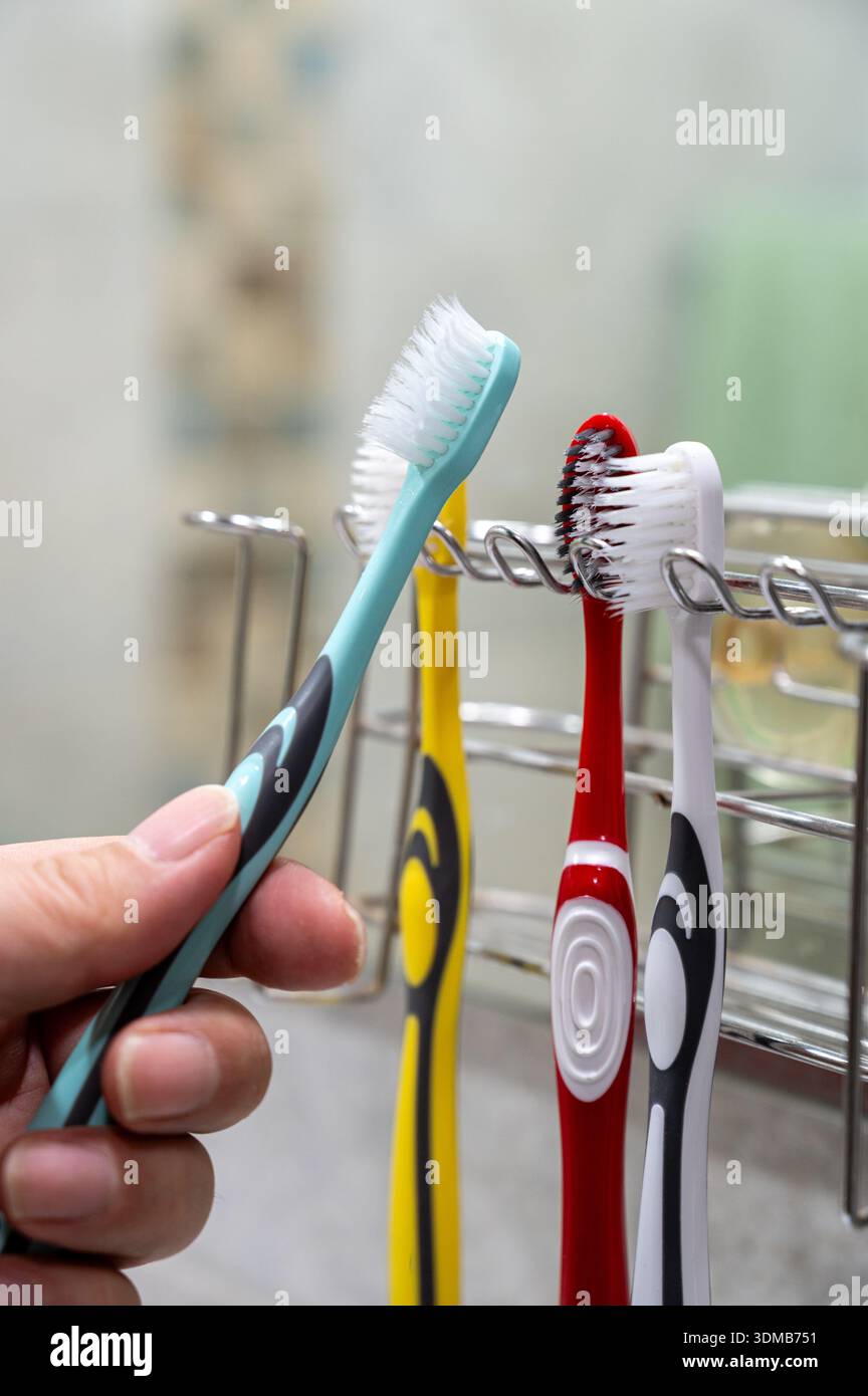 Hanging toothbrush on holder in bathroom, daily oral hygiene routine concept Stock Photo