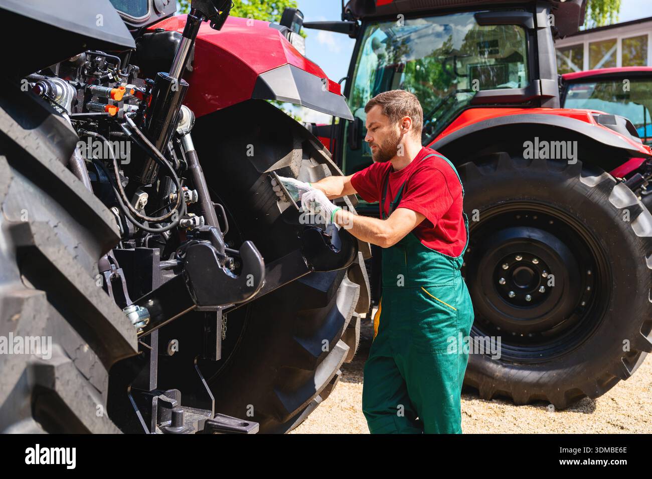 Mechanic using tablet to inspect tractor outdoors Stock Photo