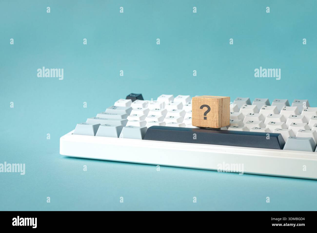 Question mark on wood block on top of keyboard. Isolated on light blue background. Stock Photo