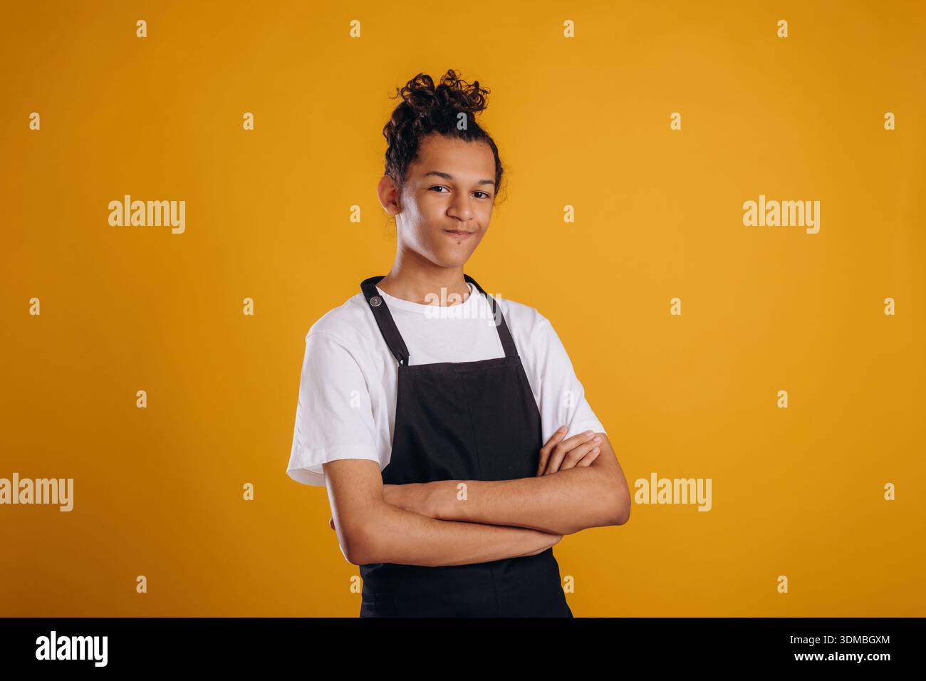 Barista is in apron. Young guy is against yellow background. Stock Photo