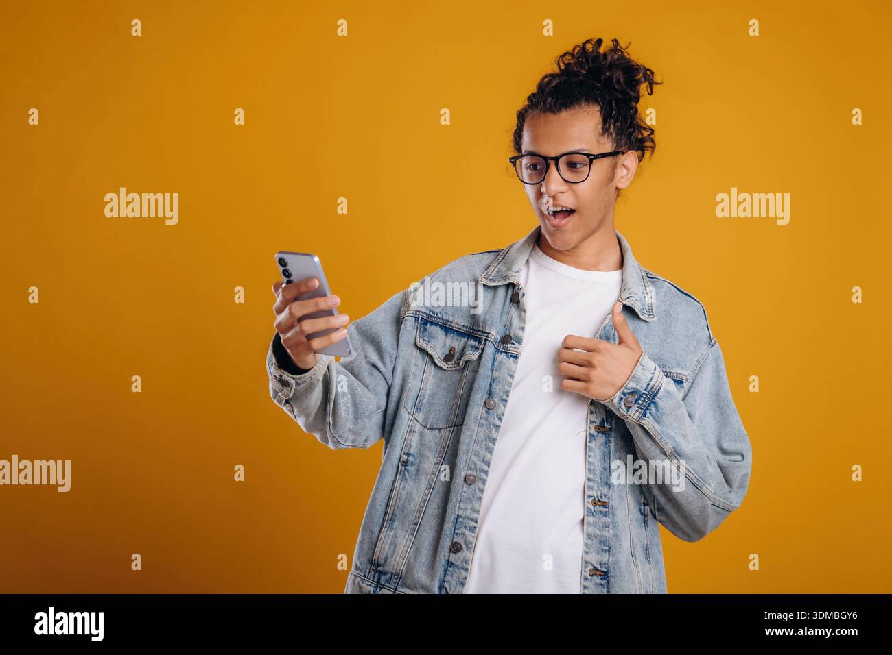 Internet conception, using smartphone. Young guy is against yellow background. Stock Photo