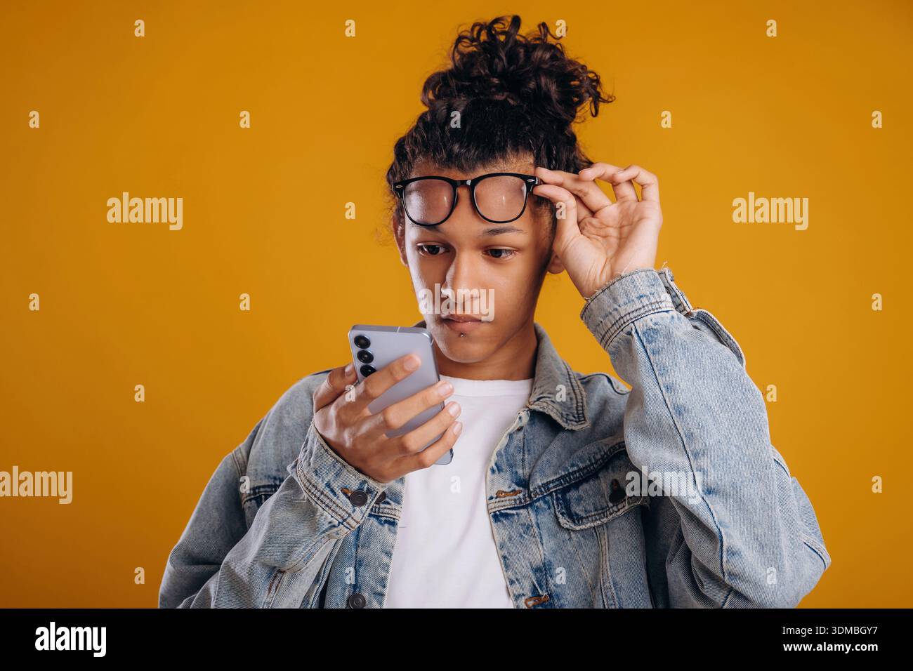 Internet conception, using smartphone. Young guy is against yellow background. Stock Photo
