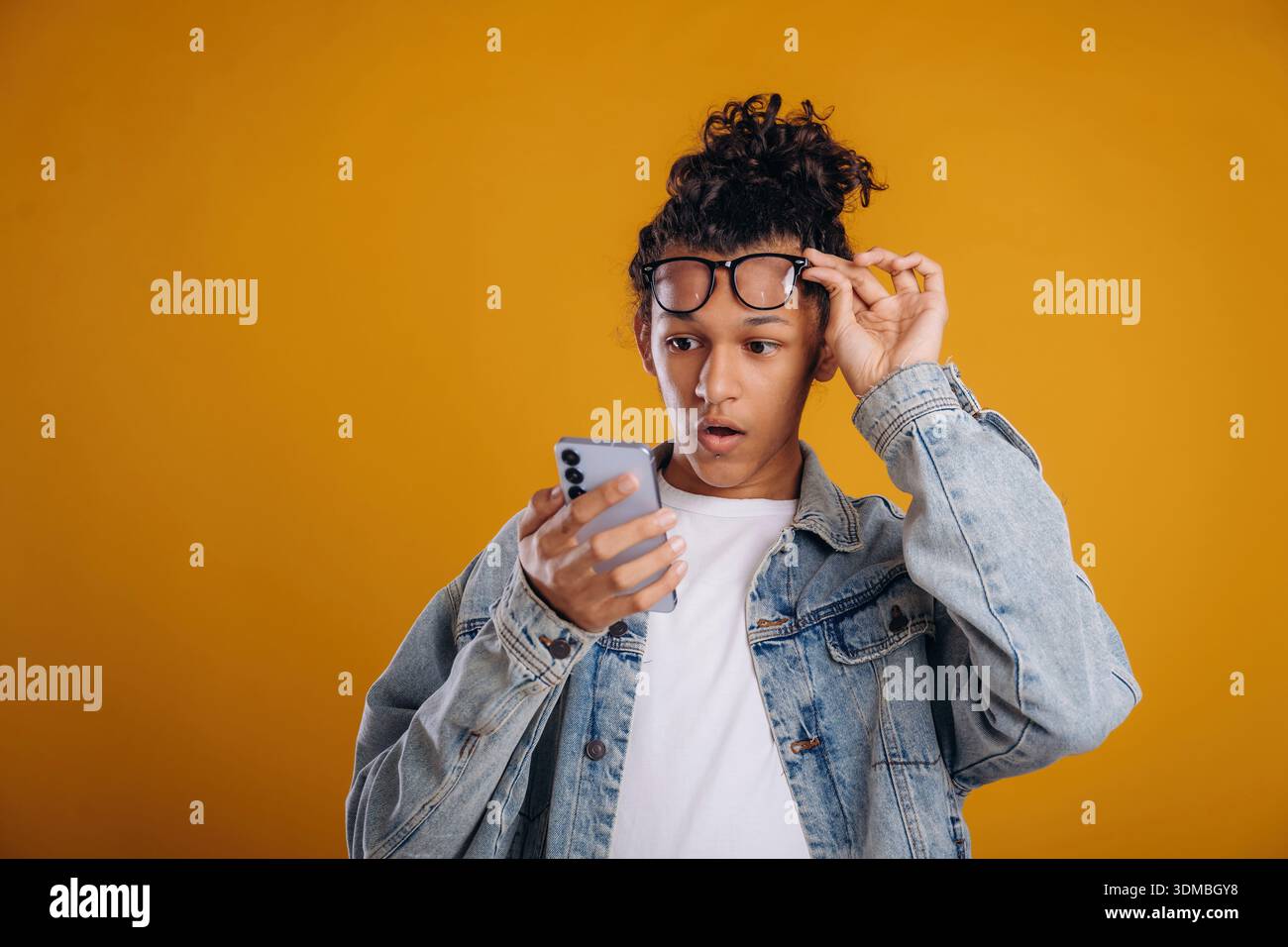Internet conception, using smartphone. Young guy is against yellow background. Stock Photo