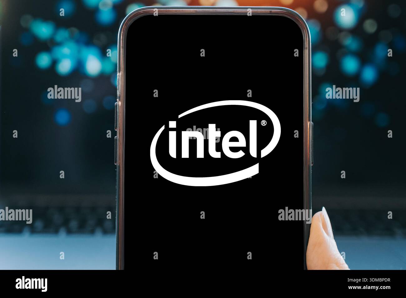 Smartphone displaying the Intel logo on a black screen, held in hand ...