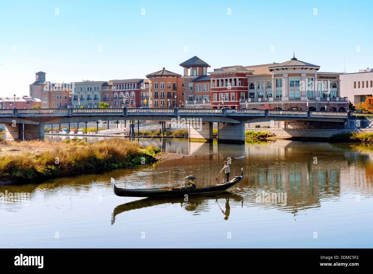 Venetian Looking Gondola, Third Street Bridge over the Napa River with downtown Napa riverfront buildings reflected in the water, Napa, Napa County, C Stock Photo