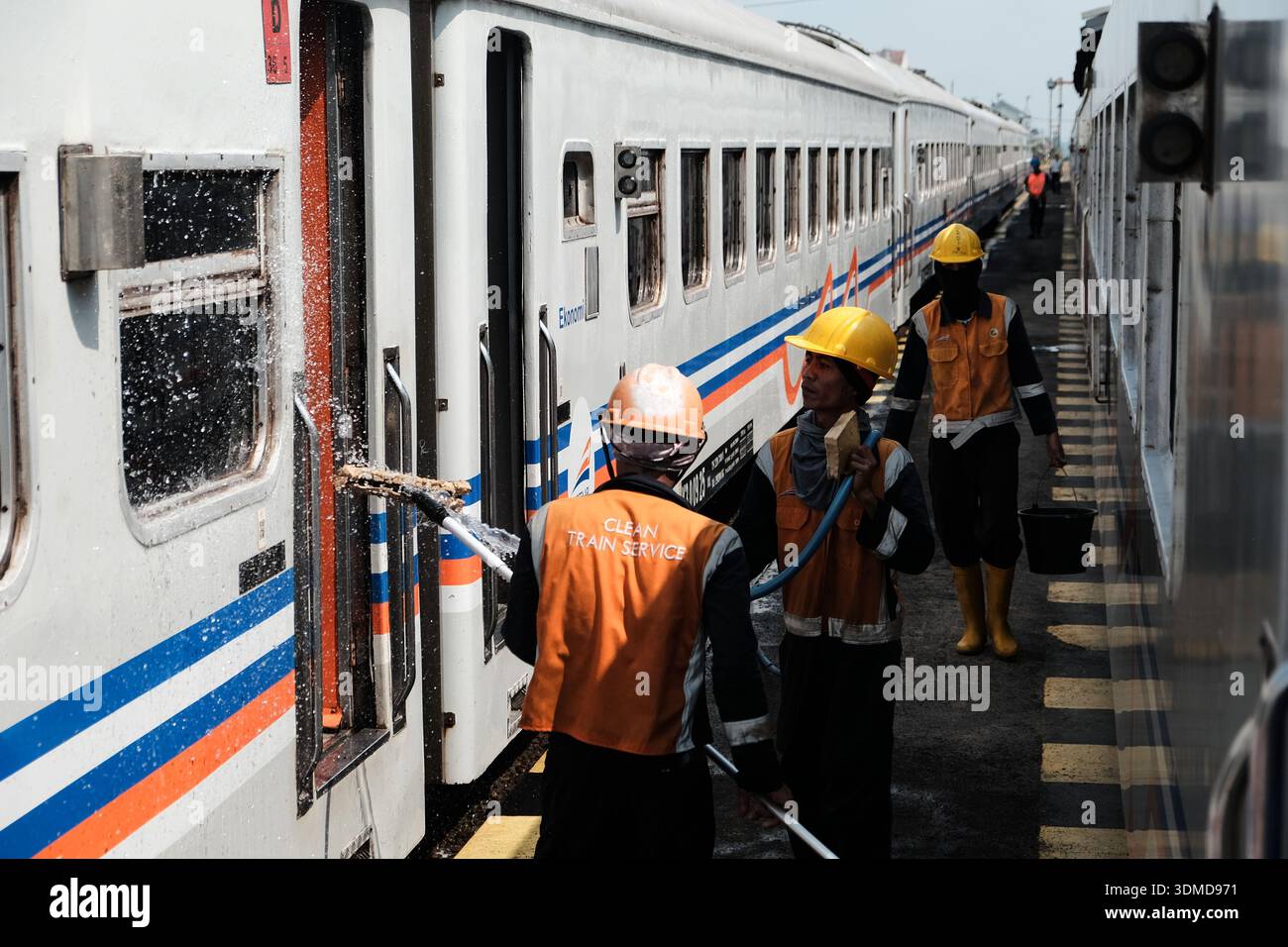 Railway workers cleaning a passenger train carriage at a station ...