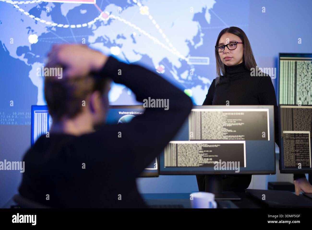 Cybersecurity professionals analyzing threat data on digital screens in control center Stock Photo
