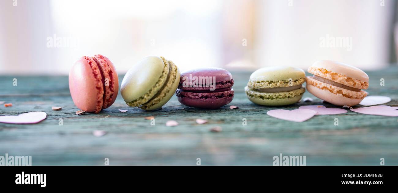 Colorful macarons arranged in a row on a old wooden table. Stock Photo