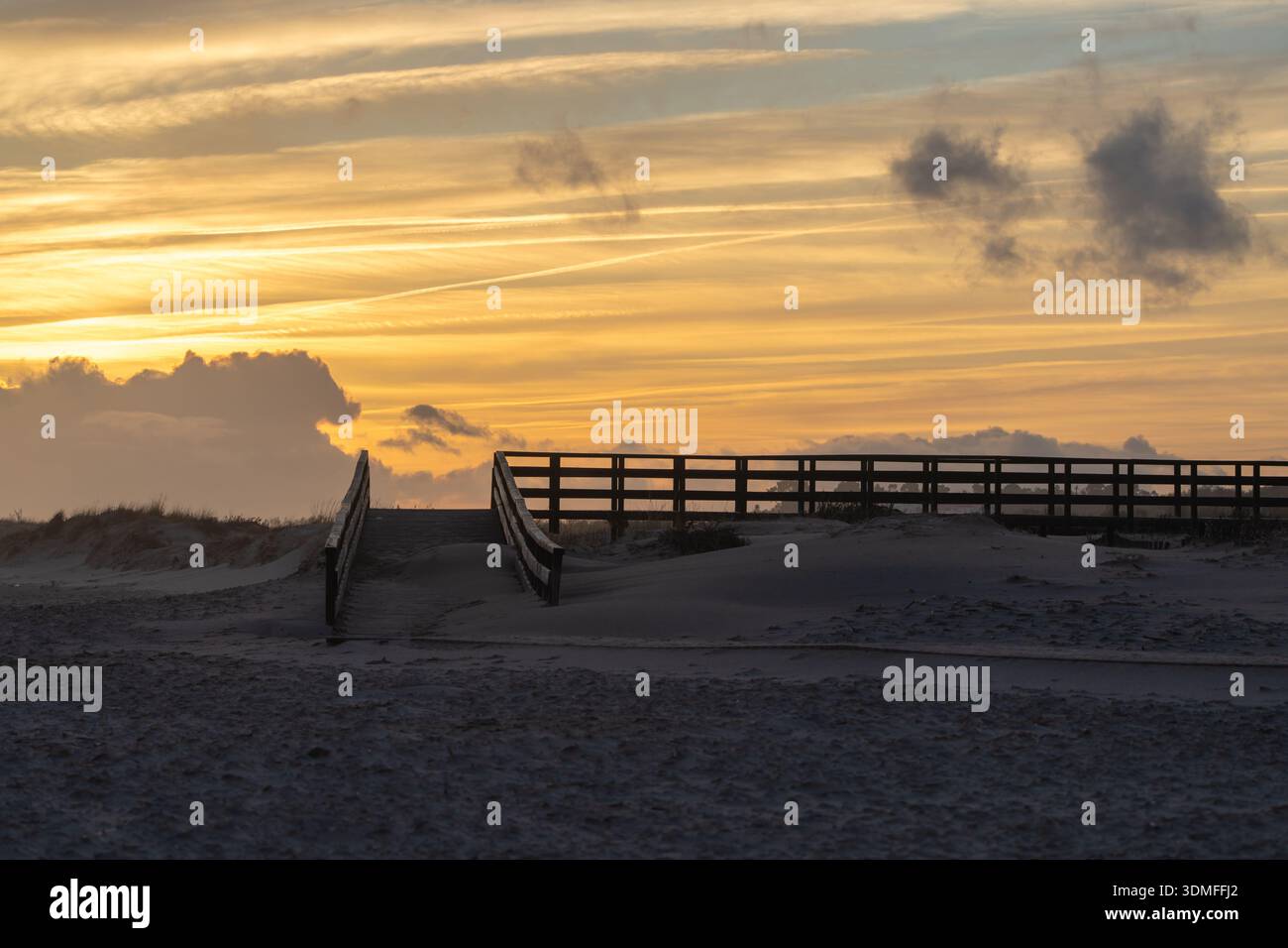 Sandy Ramps Wooden ramp leading over sandy dunes with a vibrant golden sunset sky ...