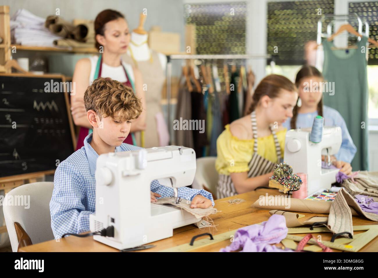 Engaged schoolboy stitching fabric on machine in sewing class Stock Photo