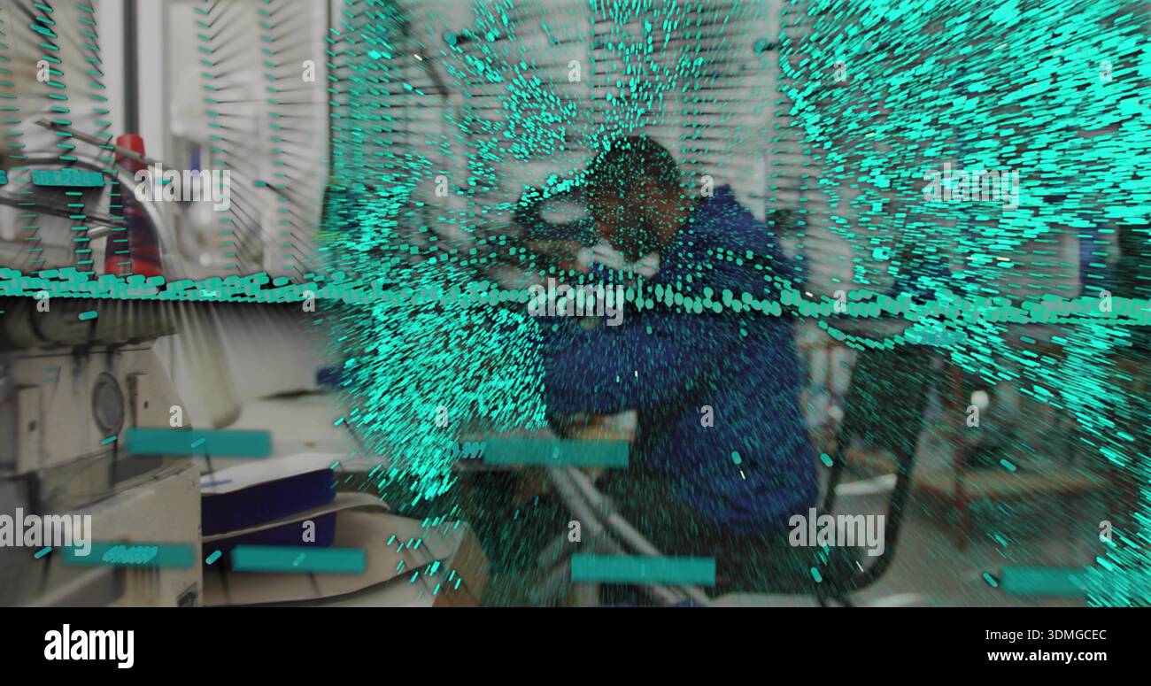 Sewing man in blue jacket operating machine at garment workshop, with teal particle overlay Stock Photo