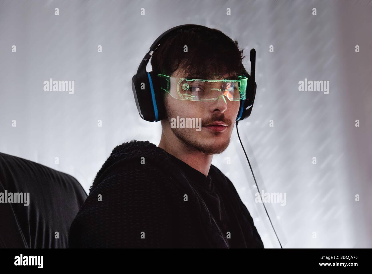 Young man using computer with led cyber glasses and headphones Stock Photo