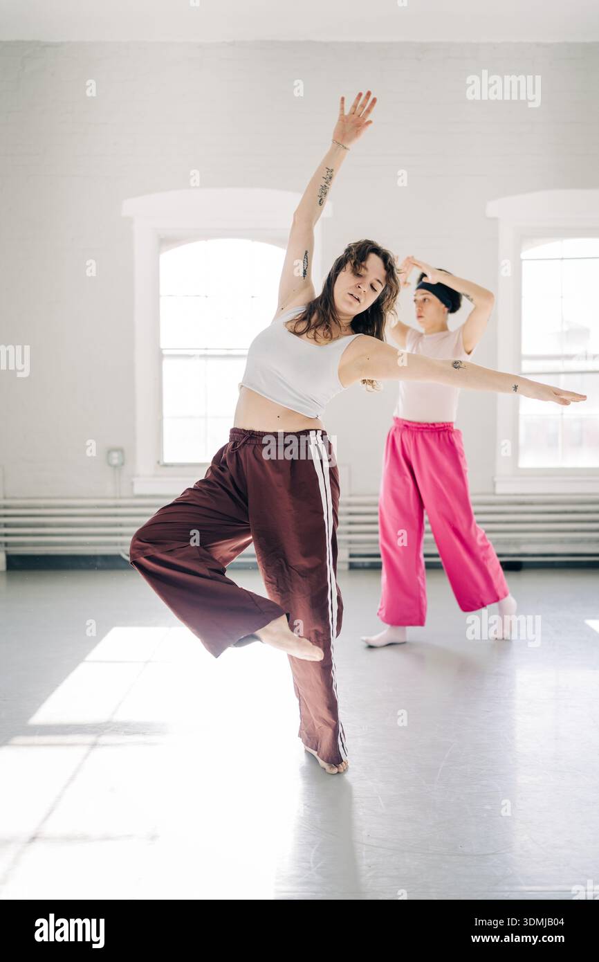 Dancers practicing modern dance in studio with sunlight Stock Photo