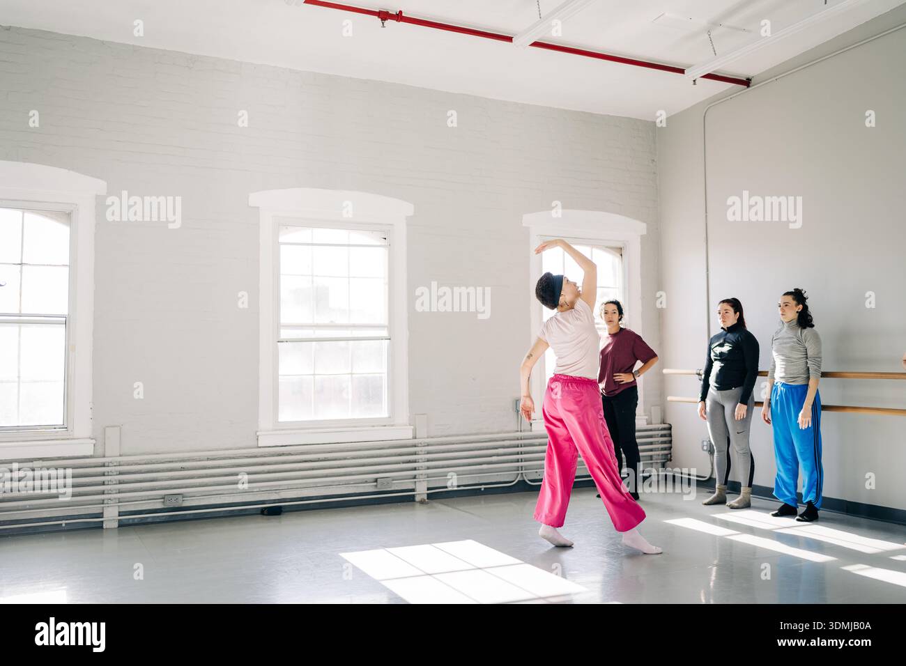Dancer practicing movement with group in studio Stock Photo