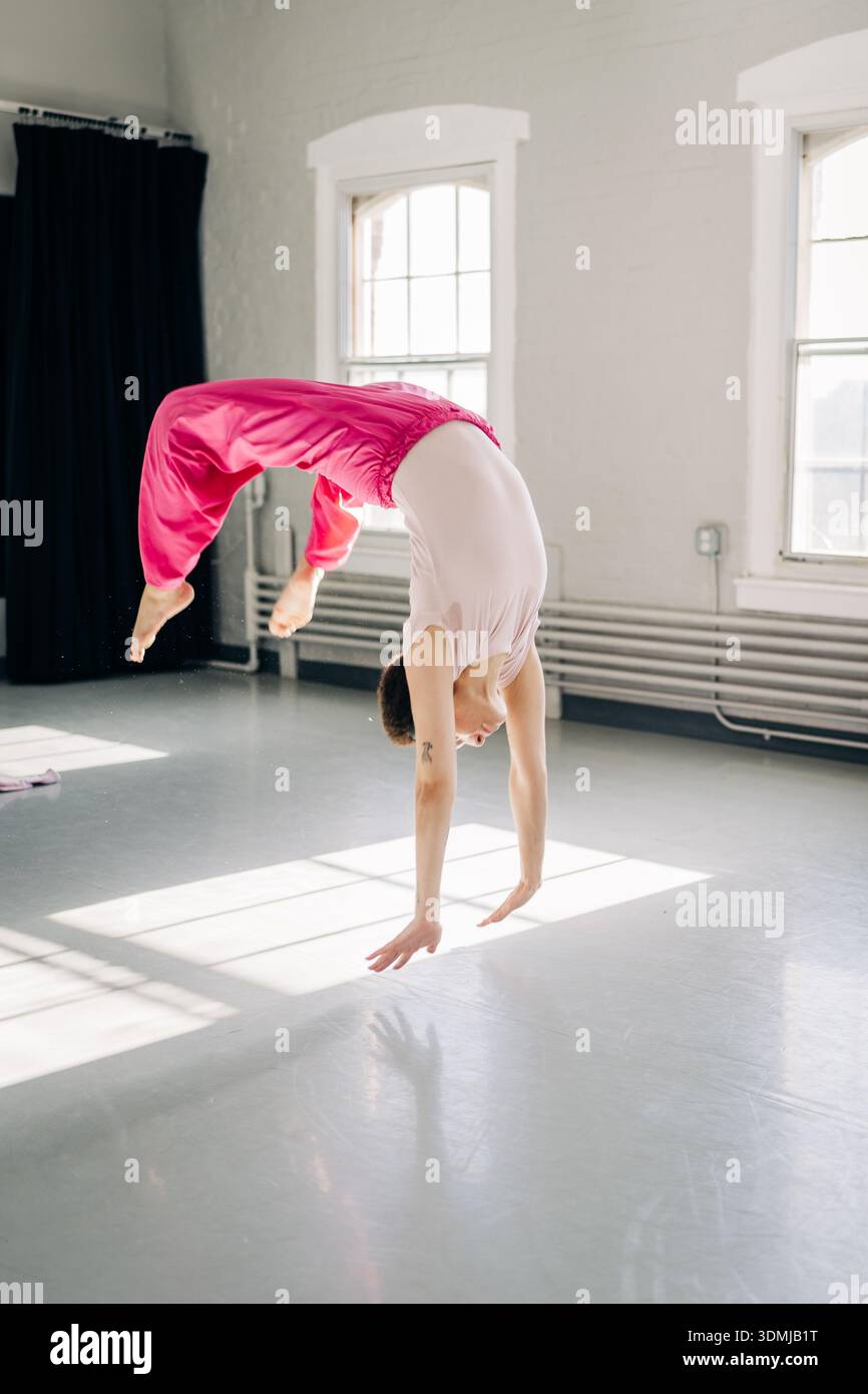 Female dancer performing a handspring in bright studio Stock Photo