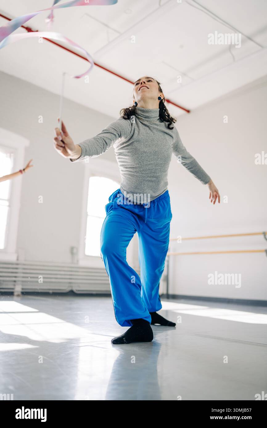 Rhythmic gymnast performing ribbon routine in studio Stock Photo