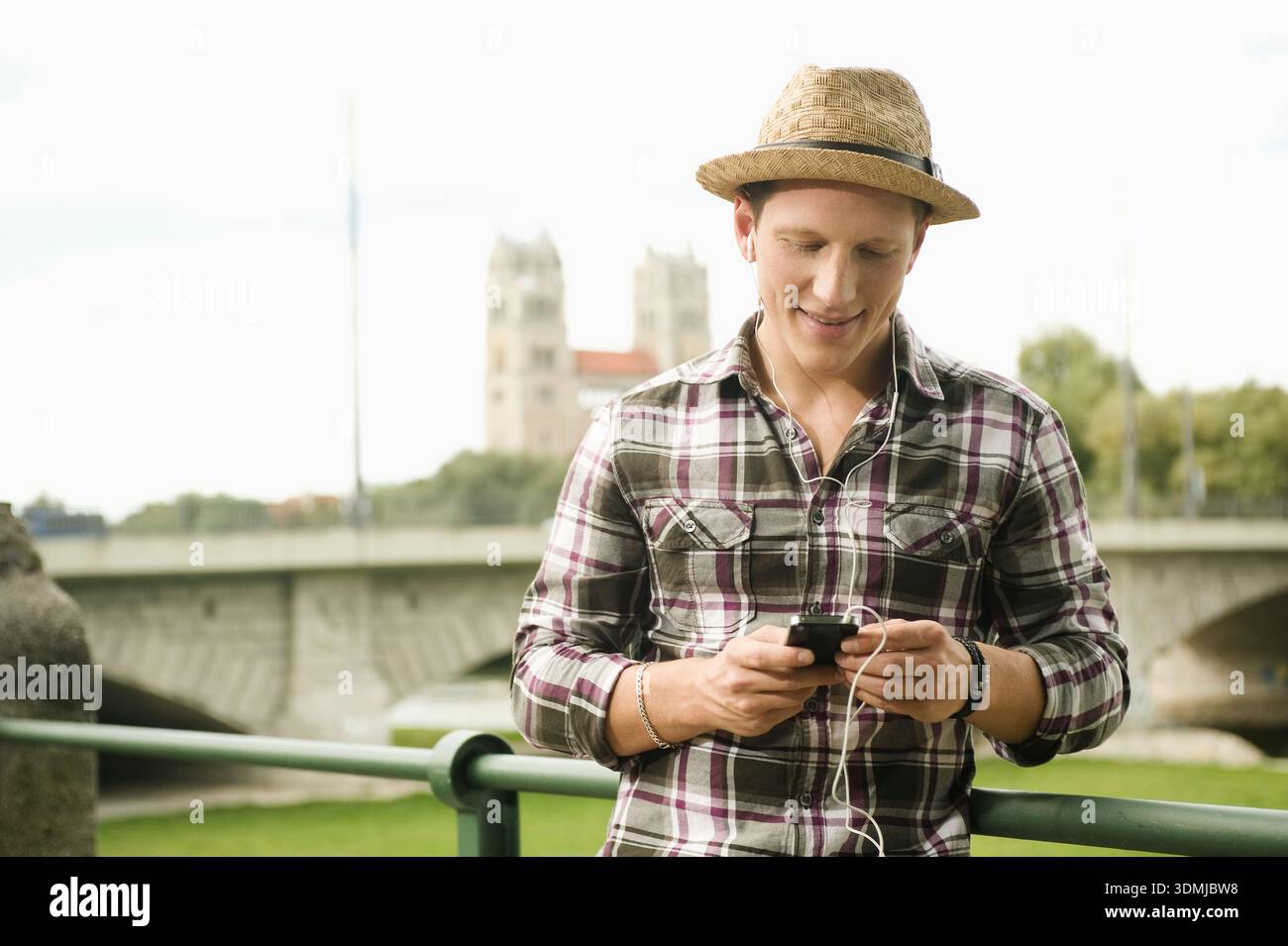 Young man with straw hat texting on his smartphone. Stock Photo