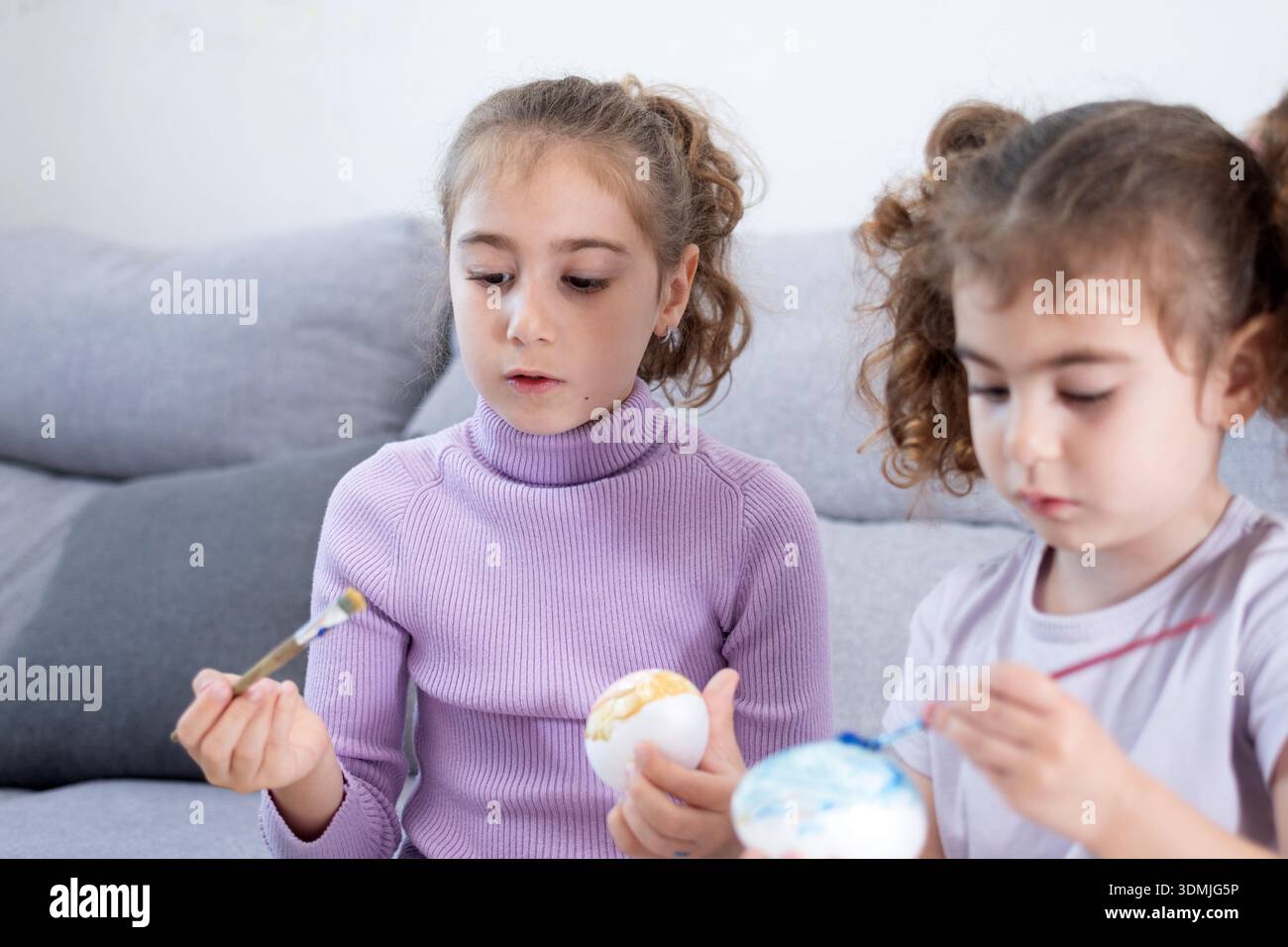 Two sisters decorating Easter eggs.at home Stock Photo