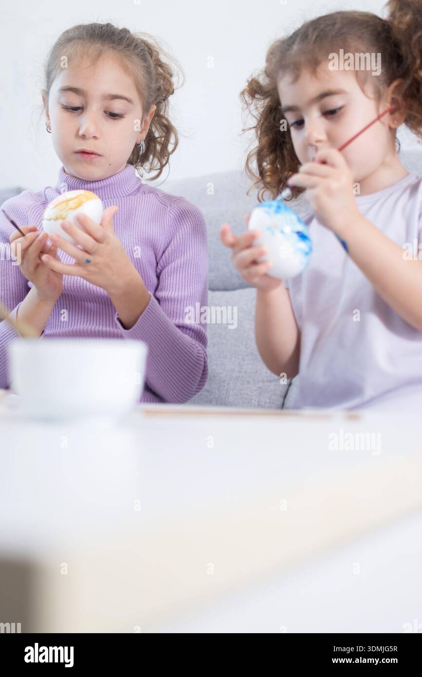 Two sisters decorating Easter eggs.at home Stock Photo
