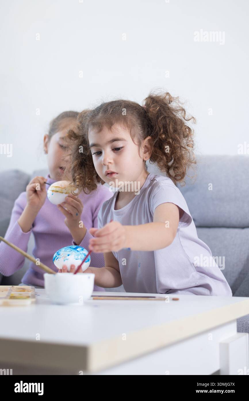 Two sisters decorating Easter eggs.at home Stock Photo