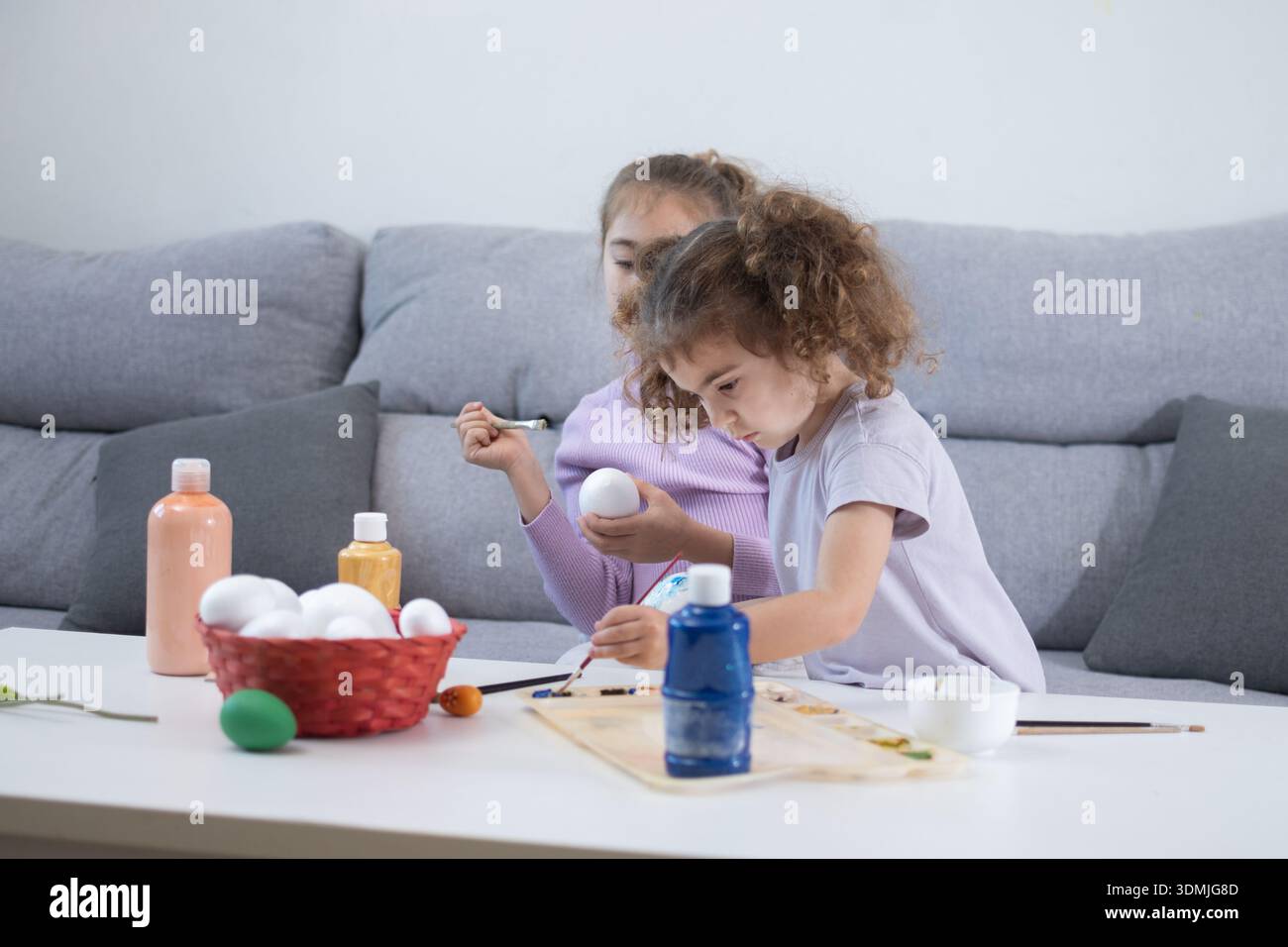 Two sisters decorating Easter eggs.at home Stock Photo