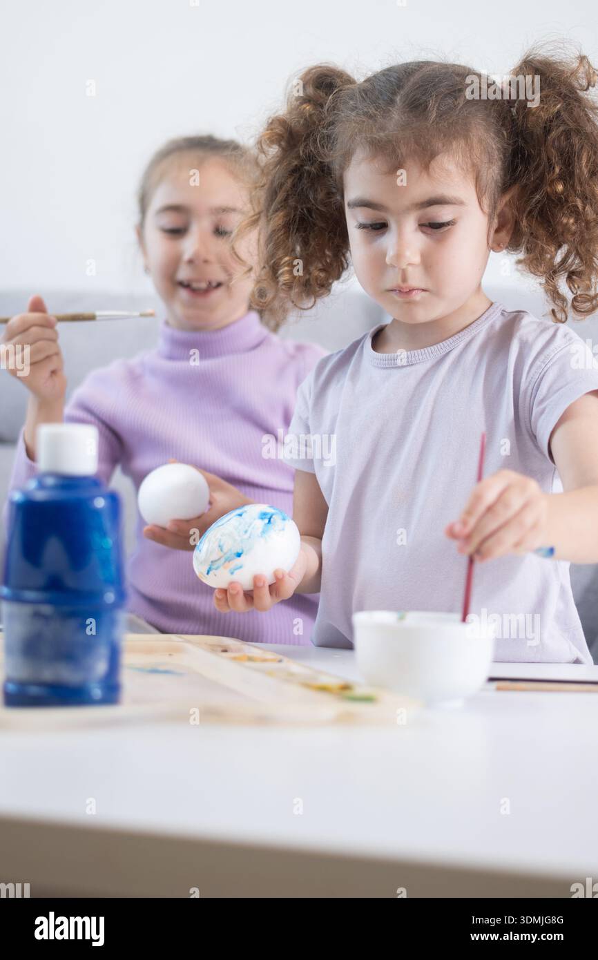 Two sisters decorating Easter eggs.at home Stock Photo