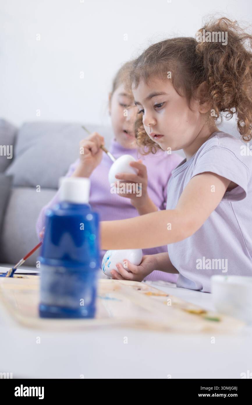 Two sisters decorating Easter eggs.at home Stock Photo