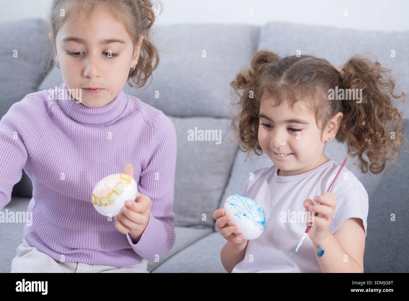 Two sisters decorating Easter eggs.at home Stock Photo