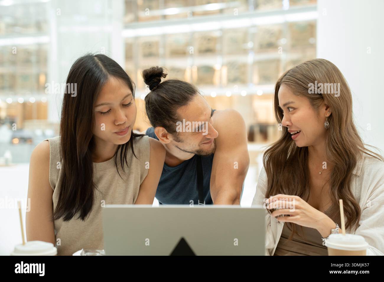 Diverse friends collaborating using laptop in cafe Stock Photo
