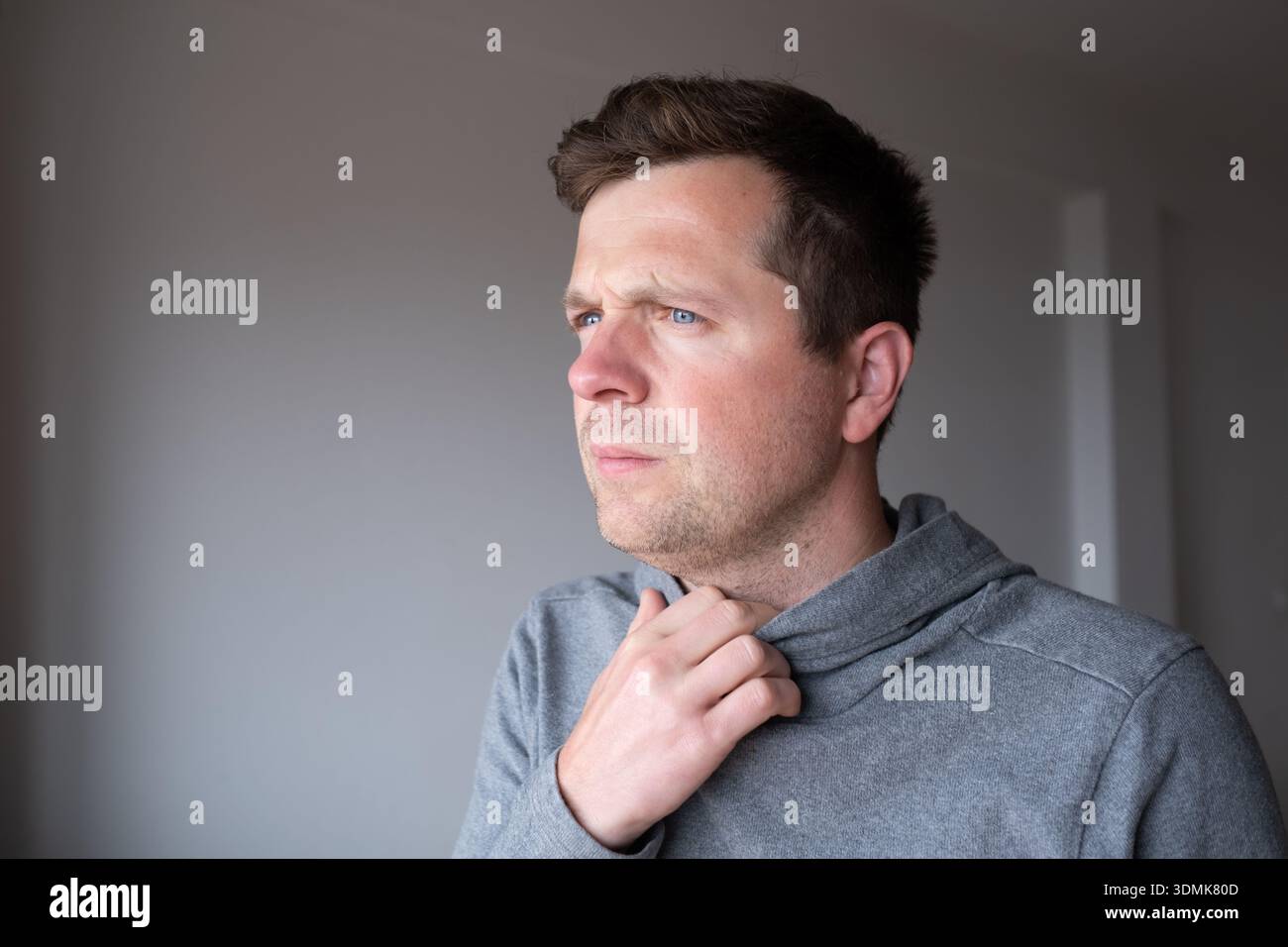 Pensive young man standing at home thinking about problems and making decisions Stock Photo