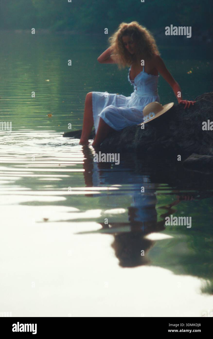 France. Dordogne. Young woman sitting on a riverbank Stock Photo - Alamy