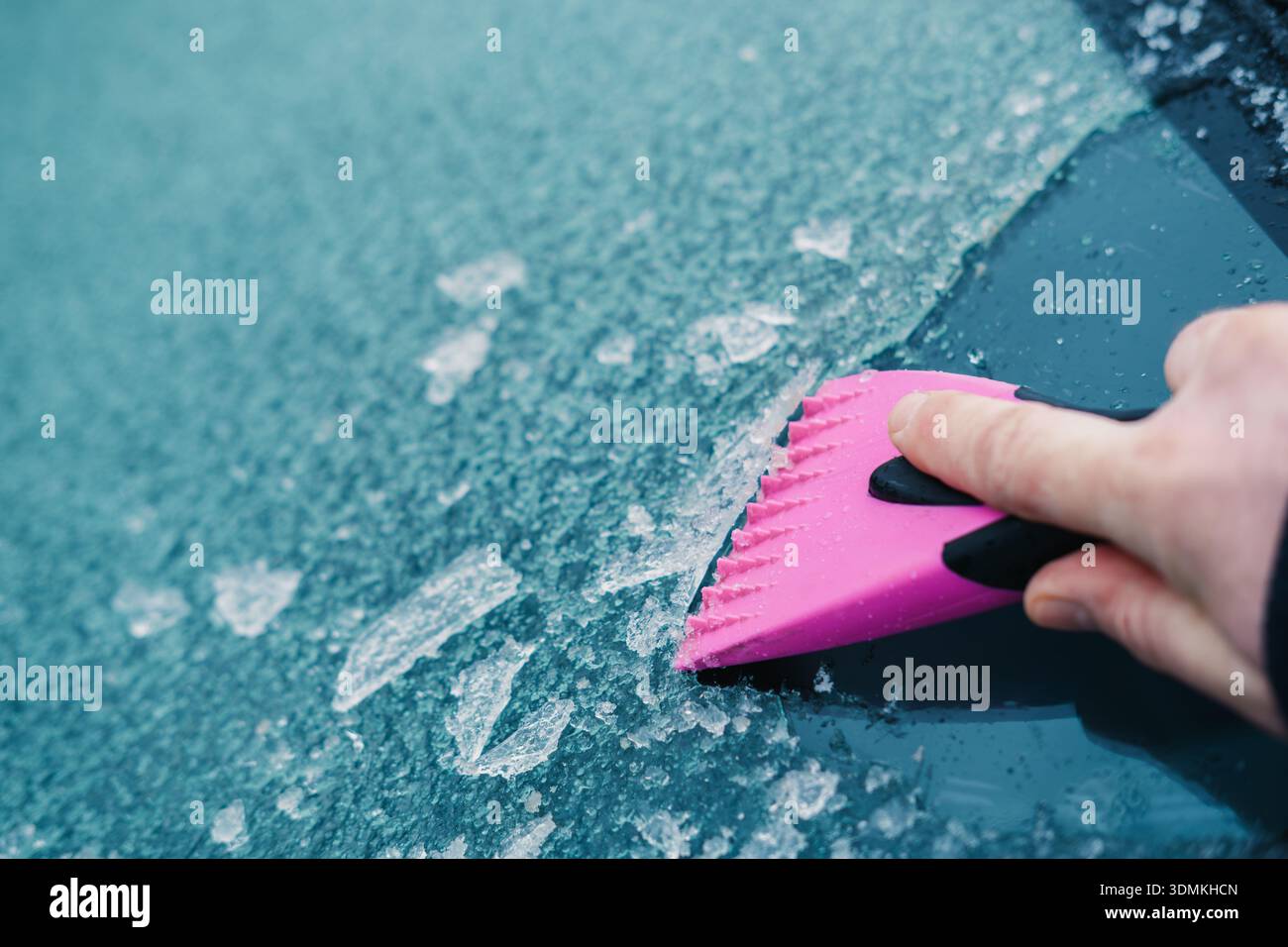 Engaging In Practical Vehicle Preparation By Clearing Icy Glass With Colorful Scraper Cold Weather Stock Photo