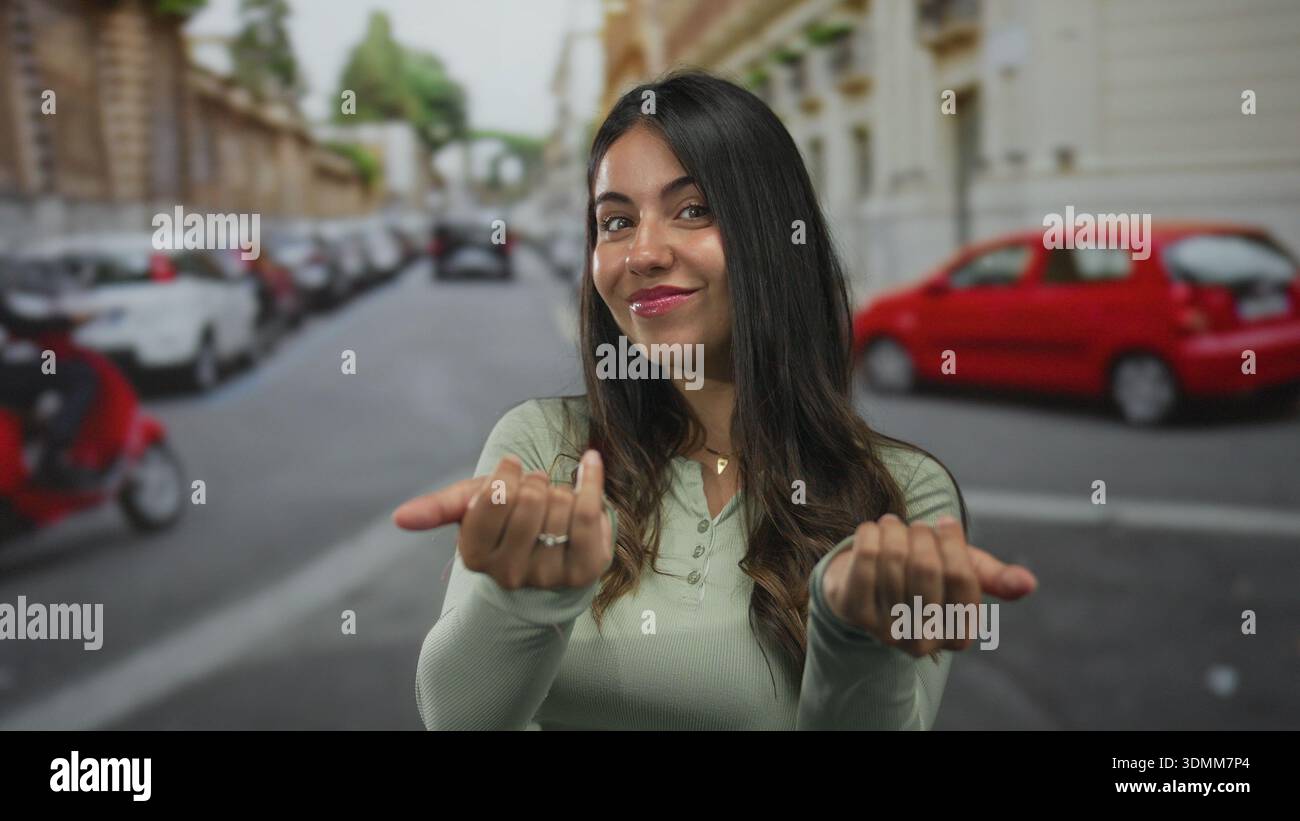 Woman beckons with hands on street in green longsleeve top near parked car; invitation welcome connection. Stock Photo