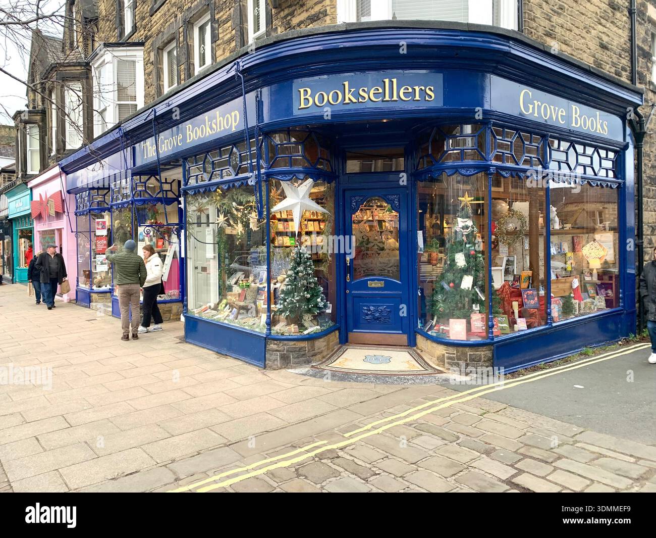 Festively decorated Grove bookshop on a winter evening in Ilkley West Yorkshire with pedestrians passing the independent booksellers corner store - Smartphone Captured Stock Image