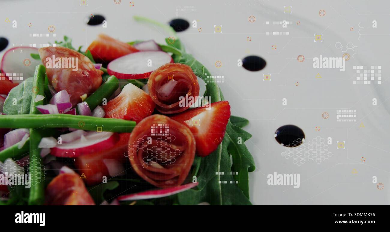 Displaying salad resting on white plate in studio, with greens, strawberries, prosciutto, balsamic Stock Photo