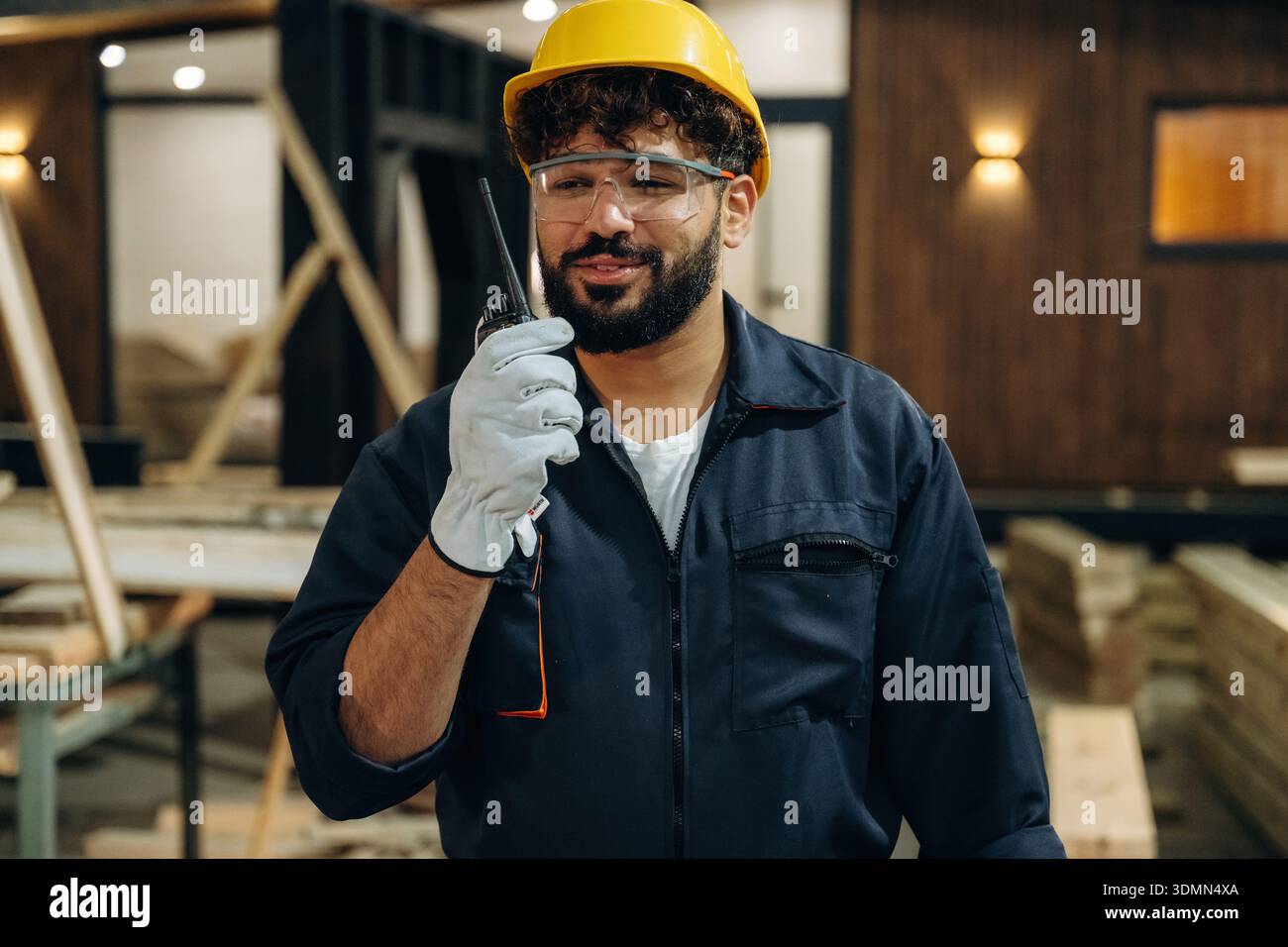 Talking by walkie talkie. Portrait of a male carpenter posing in a woodworking workshop. Stock Photo
