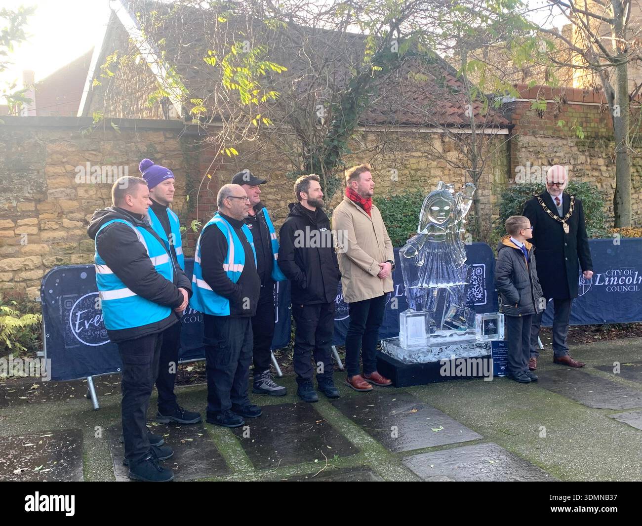 Community members gather in Lincoln of ice sculptures and the Castle walls and the mayor people talking in the street man with a top hat old buildings - Smartphone Captured Stock Image