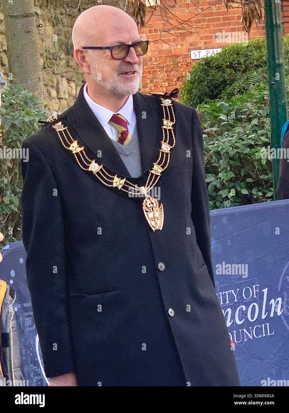 Community members gather in Lincoln of ice sculptures and the Castle walls and the mayor people talking in the street man with a top hat old buildings - Smartphone Captured Stock Image