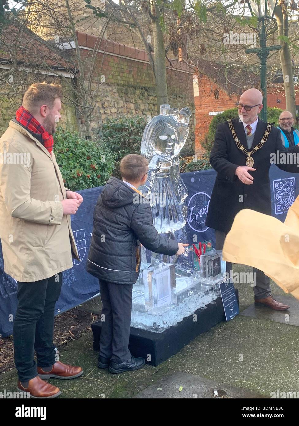 Community members gather in Lincoln of ice sculptures and the Castle walls and the mayor people talking in the street man with a top hat old buildings - Smartphone Captured Stock Image